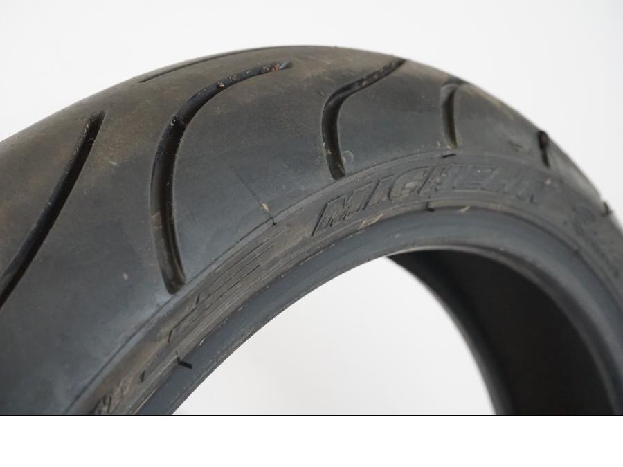 Snett nerifrån på <p>Begagnad däck av märket Michelin och modell Pilot Power 2CT.</p>
<p>Dimension 120/65-17.</p>
<p>Mönsterdjup ca: 60% (3,50mm).</p>
<p>Tillv 1022.</p> moped.