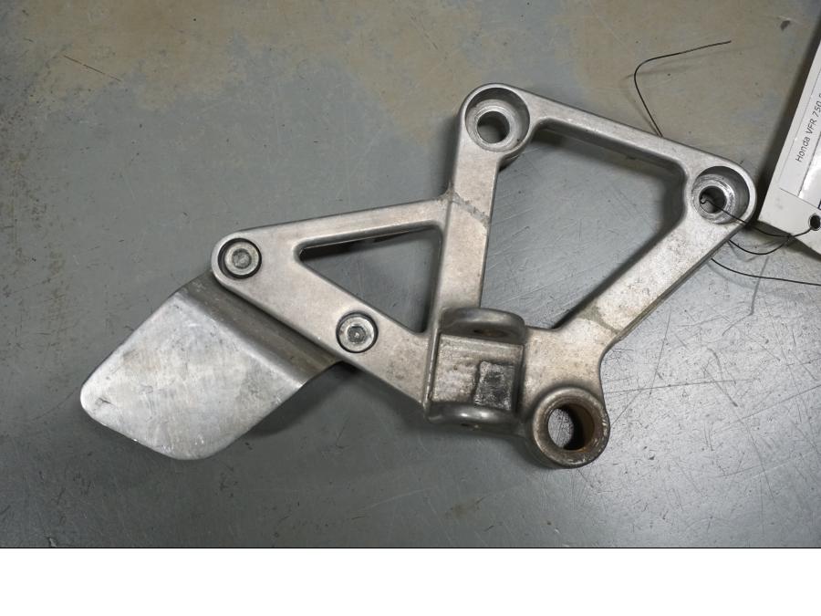 Framsidan på <p>Fotpinnefäste höger fram från Honda VFR 750 F 1988.</p>
<p>Bra skick.</p> motorcykel.