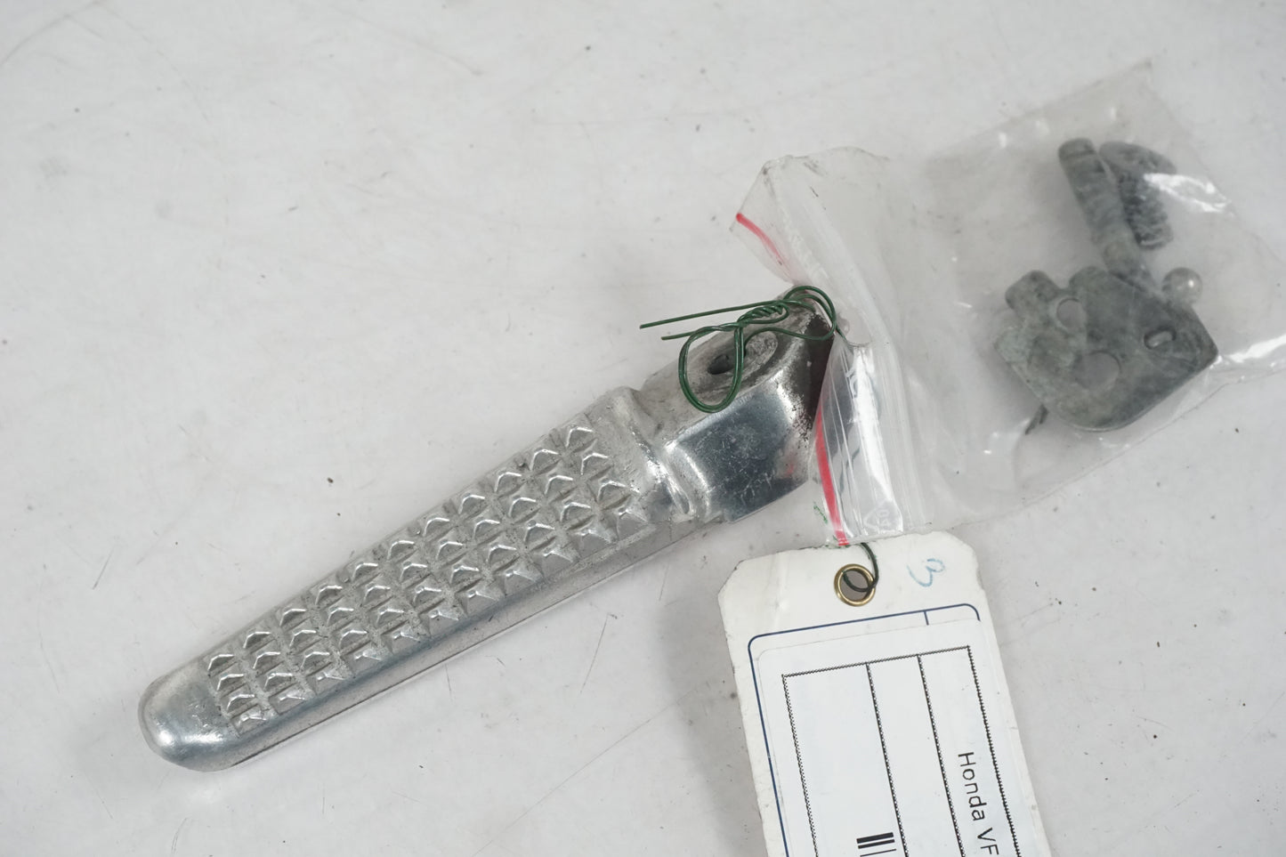 Framsidan på <p>Fotpinne vänster bak från Honda VFR 750 F 1995.</p>

<p>Okej skick.</p> motorcykel.