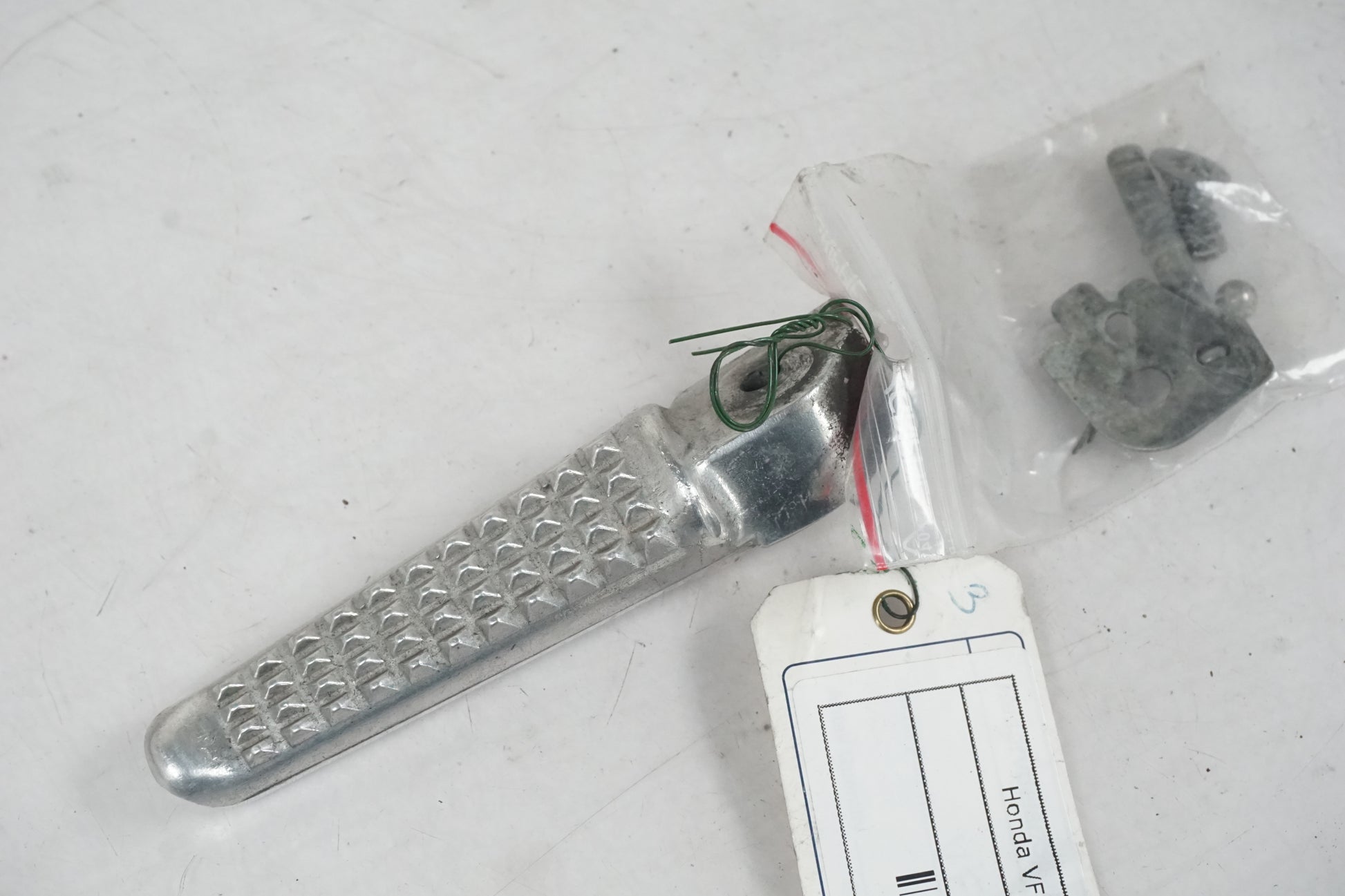 Framsidan på <p>Fotpinne vänster bak från Honda VFR 750 F 1995.</p>

<p>Okej skick.</p> motorcykel.