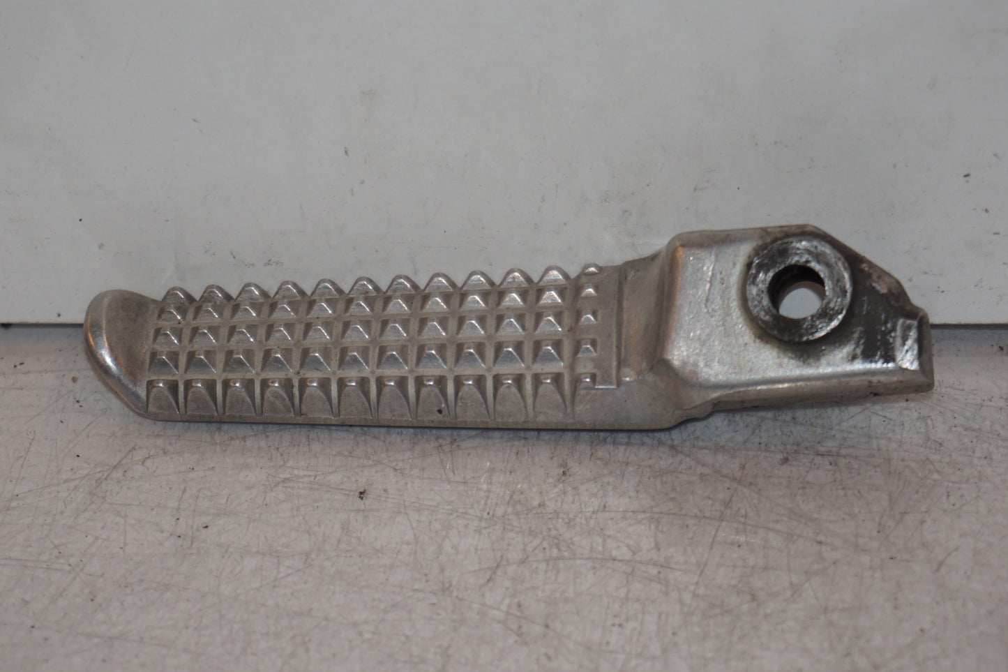 Framsidan på <p>Fotpinne höger bak från Honda VFR 750 F 1988.</p>

<p>Okej skick.</p> motorcykel.