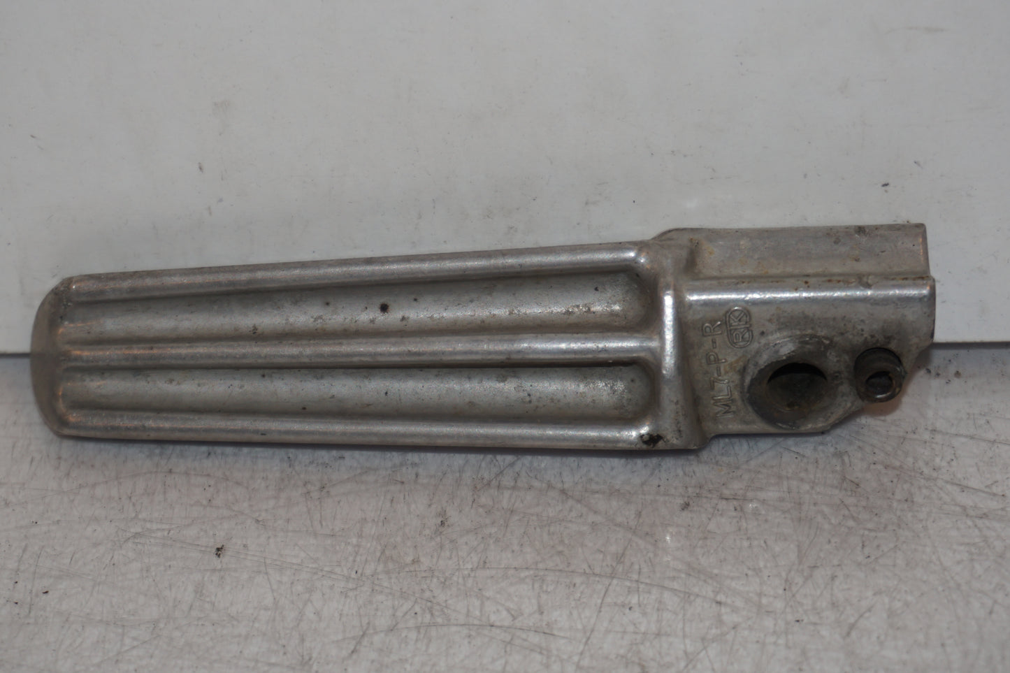 Baksidan på <p>Fotpinne höger bak från Honda VFR 750 F 1988.</p>

<p>Okej skick.</p> motorcykel.