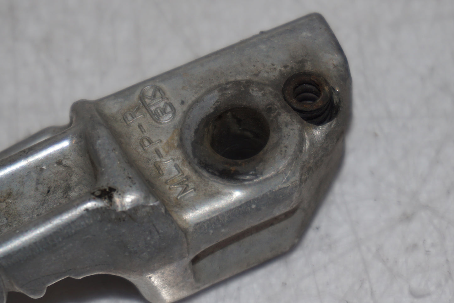 Snett nerifrån på <p>Fotpinne höger bak från Honda VFR 750 F 1988.</p>

<p>Okej skick.</p> motorcykel.