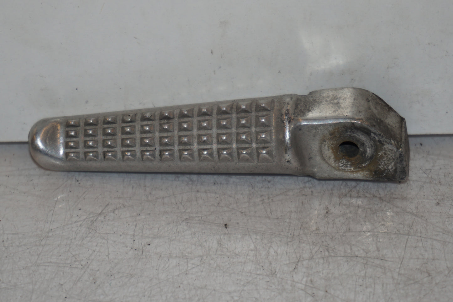 Framsidan på <p>Fotpinne höger bak från Honda VFR 750 F 1994.</p>

<p>Okej skick.</p> motorcykel.