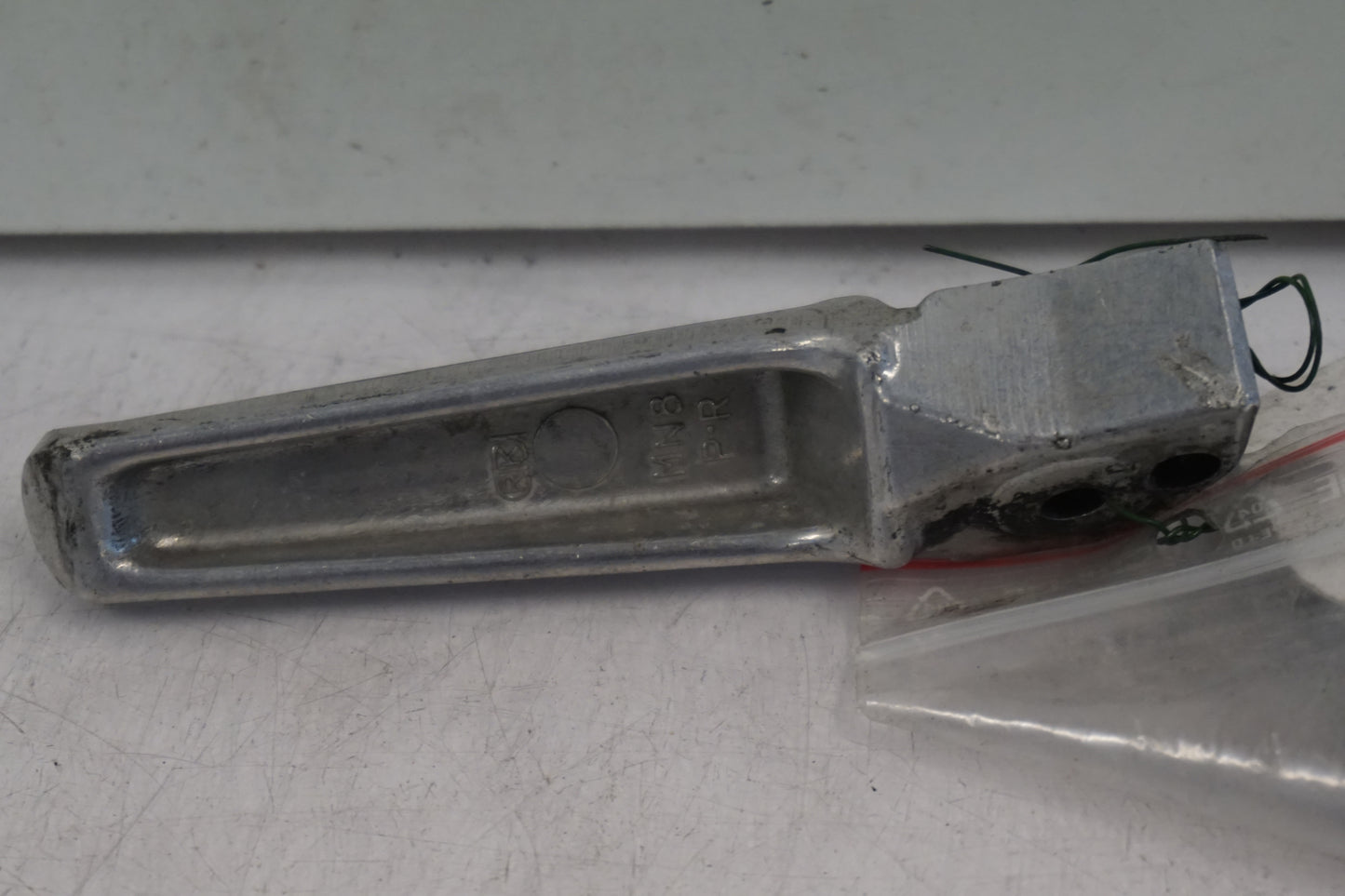 Baksidan på <p>Fotpinne höger bak från Honda VFR 750 F 1990.</p>

<p>Okej skick.</p> motorcykel.