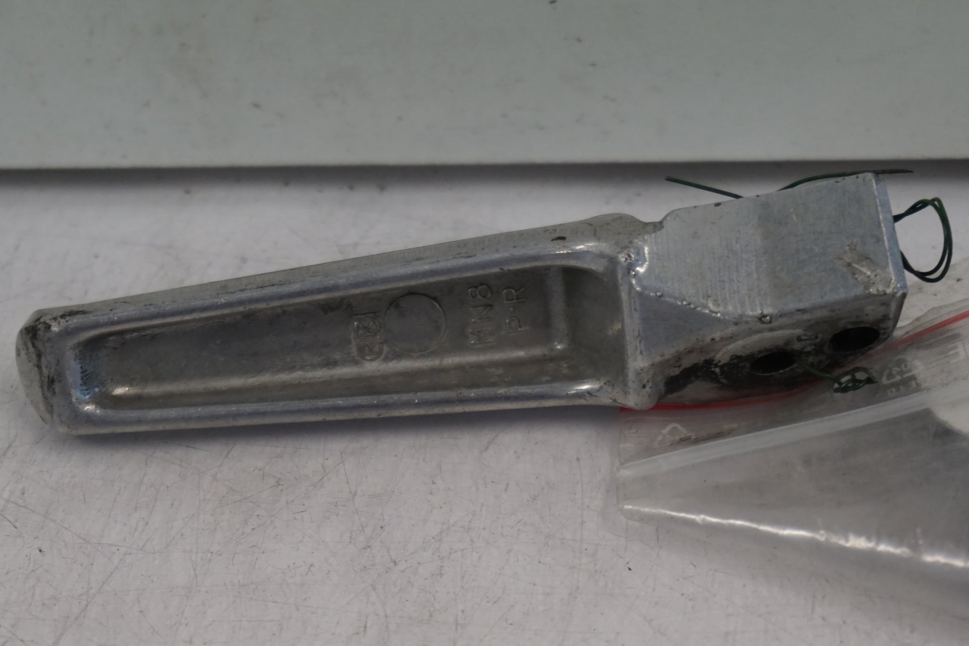 Baksidan på <p>Fotpinne höger bak från Honda VFR 750 F 1990.</p>

<p>Okej skick.</p> motorcykel.