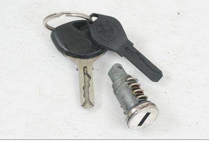 Baksidan på <p>Låssats från BMW K 1200 R Sport 2007.</p>

<p>1st nyckel och en plastkopia, sadellås, tanklock, tändningslås (saknas plastbit vid en av kontakterna).</p> motorcykel.