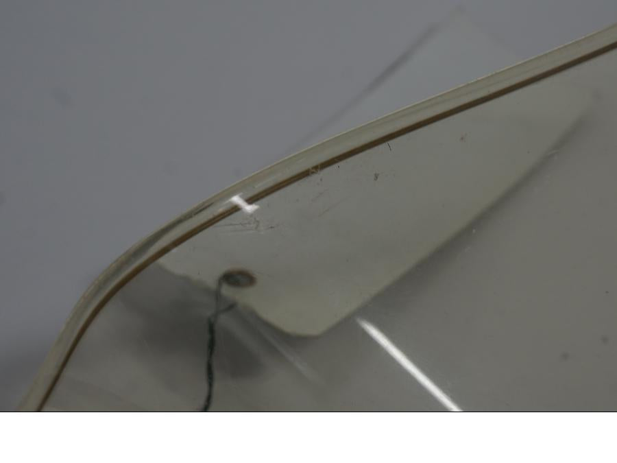 Snett nerifrån på <p>Vindruta till Aprilia RSV 1000 2002.</p>

<p>Vindrutan är solblekt och har en gul "toning" sen vanlig transparant färg beroende på från vilken vinkel man kollar på den.</p>

<p>Ytliga repor / repor finns se bilder.</p> motorcykel.