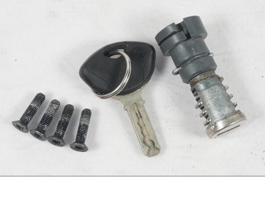 Baksidan på <p>Låssats från BMW F 800 R 2011.</p>

<p>Tändningslås, antenn, tanklock med repor, sadellås och 1st nyckel. Ytliga repor finns på tanklocket.</p> motorcykel.