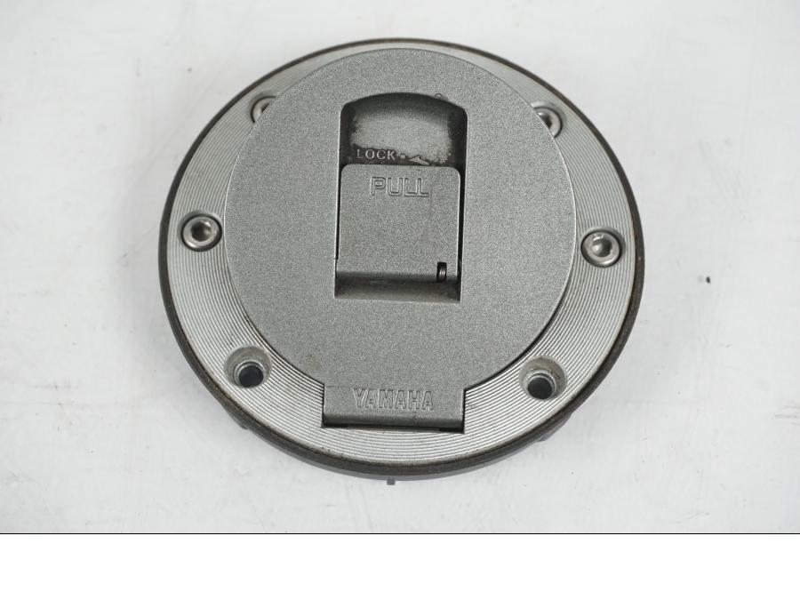 Snett nerifrån på <p>Tanklock från Yamaha FZ-S 600 1998.</p>

<p>Med 1st nyckel och sadellås.</p> motorcykel.