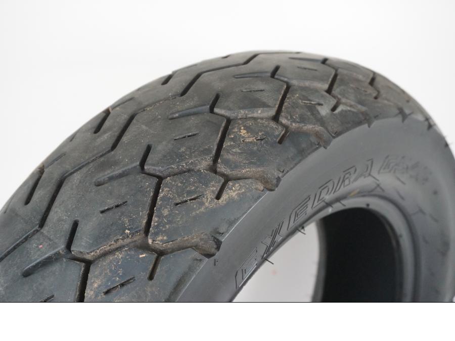 Snett uppifrån på <p>Begagnad däck av märket Bridgestone och modell Exedra G546.</p>

<p>Dimension 170/80-15 M/C 77S. </p>

<p>Mönsterdjup ca: 4,00mm.</p>

<p>Mönsterdjup yttre kanter ca: 5,40mm.</p>

<p>Tillv: Vecka 44 år 2014.</p> moped.