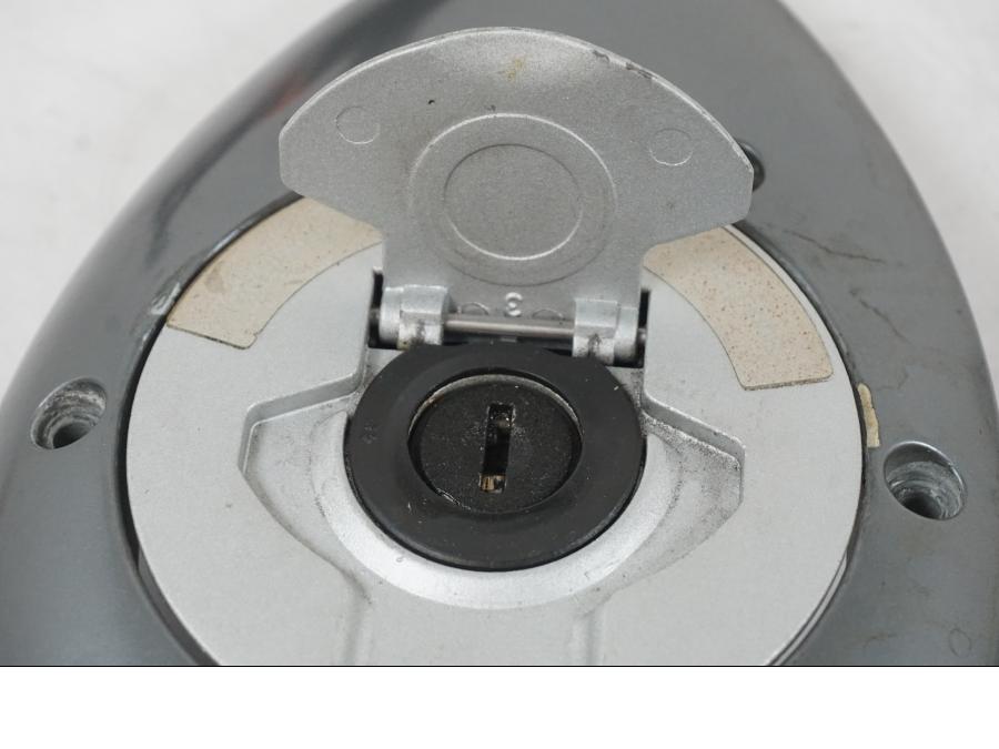 Snett uppifrån på <p>Låssats från BMW R 1200 C 2002.</p>

<p>Tändningslås, tanklock, ett väsklås, skador finns och 2st nycklar. Lacksläpp på tändningslåset se bild.</p> motorcykel.