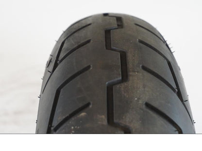 Snett nerifrån på <p>Begagnad däck av märket Michelin och modell Scorcher "31" Harley Davidson.</p>

<p>Dimension 130/70-18.63H </p>

<p>Mönsterdjup ca.4mm 70%</p>

<p>Tillv.03/2022</p> moped.