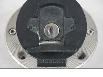 Snett uppifrån på <p>Låssats från Suzuki TL 1000 S 1997.</p>

<p>Tändningslås, tanklock, sadellås och 1st nyckel.</p>

<p>Repor finns på tanklocket, slitage av lack på tändningslåset även att gummi skyddet för kabel har ett hål se bild.</p> motorcykel.