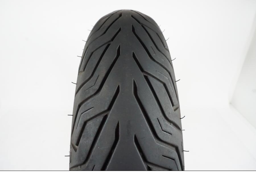 Baksidan på <p>Däck: MIchelin City Grip.</p>

<p>Dimension: 130/70-16 M/C 61P.</p>

<p>Tillv. 4216.</p>

<p>Mönsterdjup: ca. 50 %, vissa torrsprickor finns.</p> motorcykel.