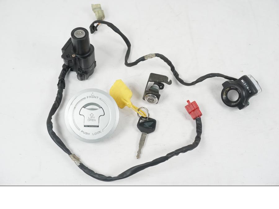 Framsidan på <p>Låssats från Honda XL 650 V 2000.</p>

<p>1st nyckel, tändningslås, sadellås, tanklock/lås.</p>

<p>HISS antenn. Slitage av lack på tändningslåset se bild.</p> motorcykel.