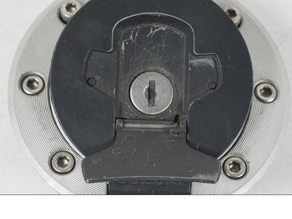 Snett uppifrån på <p>Tanklock från Suzuki GSX 750 W 2002.</p>

<p>Med 1st nyckel. Repor finns på tanklocket se bilder.</p> motorcykel.