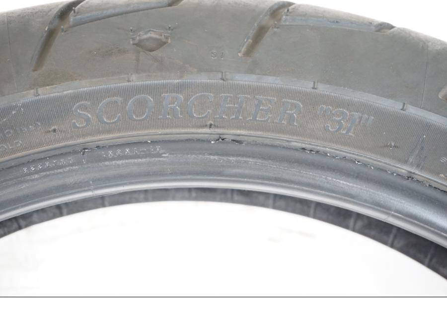 Baksidan på <p>Begagnad däck av märket Michelin och modell Scorcher "31" Harley Davidson.</p>

<p>Dimension 130/70-18.63H </p>

<p>Mönsterdjup ca.4mm 70%</p>

<p>Tillv.03/2022</p> moped.