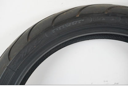 Vänster sida på <p>Begagnad däck av märket Michelin och modell Pilot Power 2CT.</p>

<p>Dimension 110/70ZR17 M/C (54W). </p>

<p>Mönsterdjup ca: 3,00mm.</p>

<p>Mönsterdjup yttre kant ca: 3,75mm.</p>

<p>Tillv: vecka 33 år 2021.</p> moped.