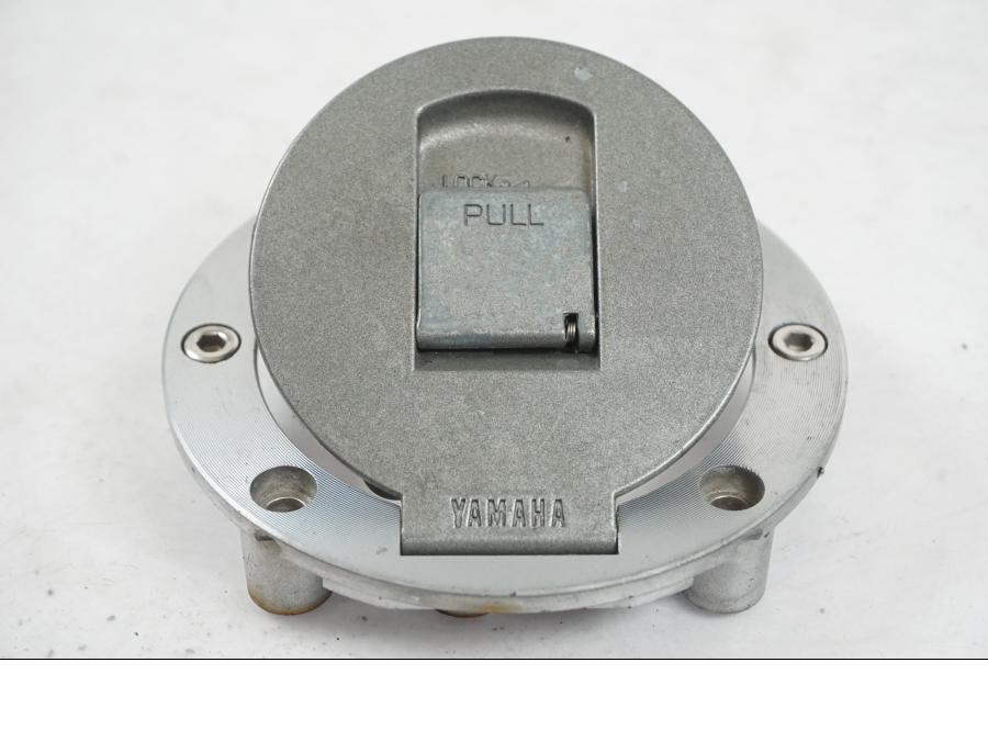 Vänster sida på <p>Låssats från Yamaha FJ 1200 1986.</p>

<p>Tändningslås. Tanklock, 1st nyckel.</p>

<p>Repor och slitage av lack på tändningslåset samt att gummiskyddet för vajrarna har ett mindre hål se bilder.</p> motorcykel.