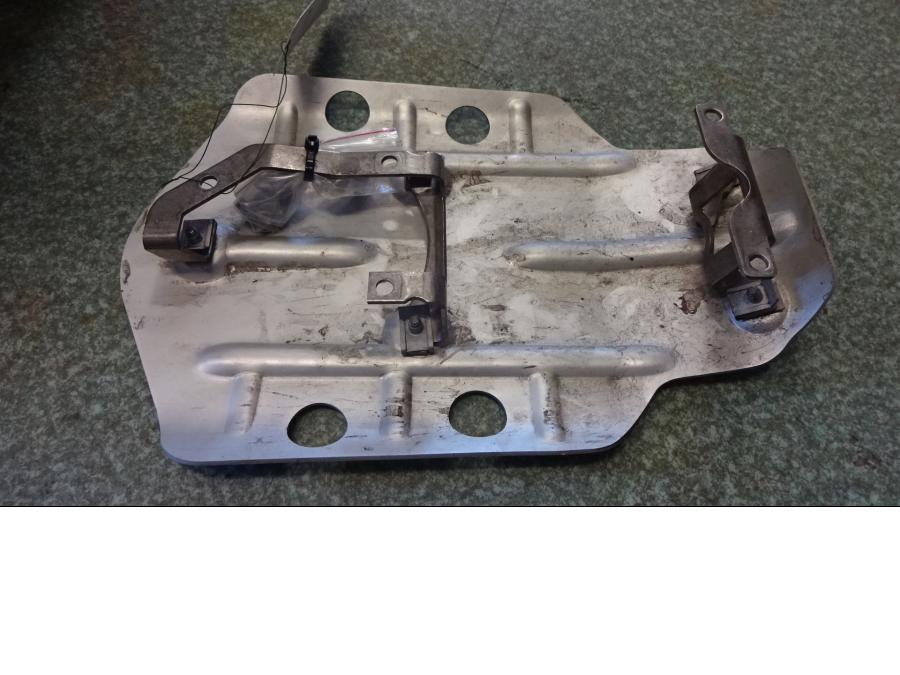 Framsidan på <p>Hasplåt från BMW R 1200 GS 2013.</p>

<p>Med fästen och bult, några repor på undersidan.</p> motorcykel.