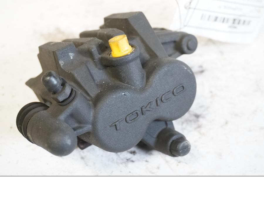 Framsidan på <p>Bromsok vänster fram från Kawasaki ER-6N ABS 2010.</p>

<p>Tokico. Två kolvs ok. Okej skick.</p> motorcykel.