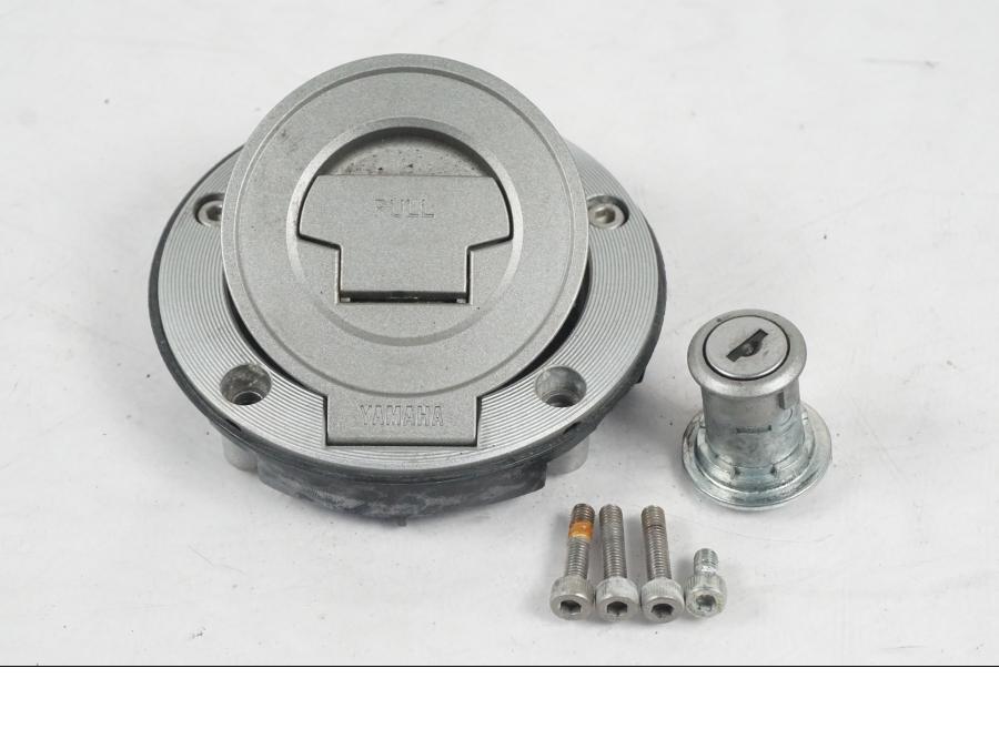 Baksidan på <p>Låssats från Yamaha XT 1200 Z ABS 2011.</p>

<p>Cdi, tändningslås, antenn, tanklock, sadellås, toppboxlås och 3st nycklar. Finns en skada på sadellåsmekanismens skyddsgummi se bild.</p> motorcykel.