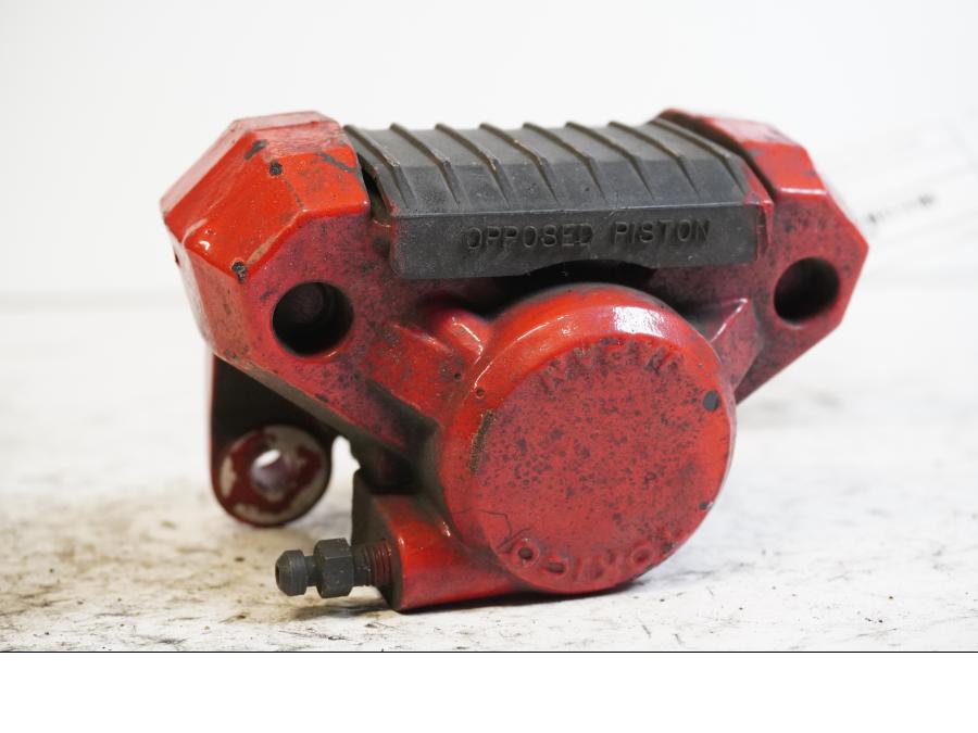 Framsidan på <p>Bromsok bak från Suzuki GSX-R 750 W 1995.</p>

<p>Tokico 2-kolv, rödmålad.</p> motorcykel.