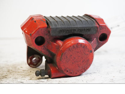 Framsidan på <p>Bromsok bak från Suzuki GSX-R 750 W 1995.</p>

<p>Tokico 2-kolv, rödmålad.</p> motorcykel.