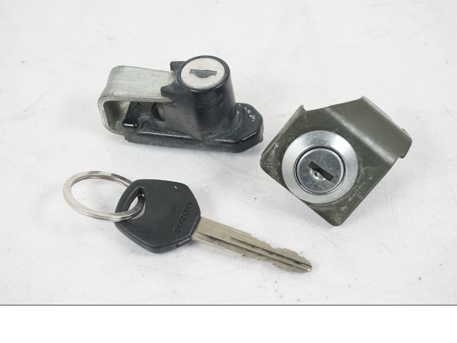 Baksidan på <p>Låssats från Suzuki DL 1000 2004.</p>

<p>1st nyckel, tändningslås, sadellås, tanklock och hjälmlås.</p> motorcykel.