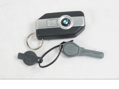 Baksidan på <p>Låssats från BMW R 1200 RS 2015.</p>

<p>Keyless Ride, tändningslås, en grå plastnyckel, tanklock, antenn, kablage, fjärrnyckel och sadellås.</p> motorcykel.