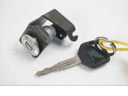 Baksidan på <p>Låssats från Honda XL 650 V 2000.</p>

<p>1st nyckel, tändningslås, sadellås, tanklock/lås.</p>

<p>HISS antenn. Slitage av lack på tändningslåset se bild.</p> motorcykel.