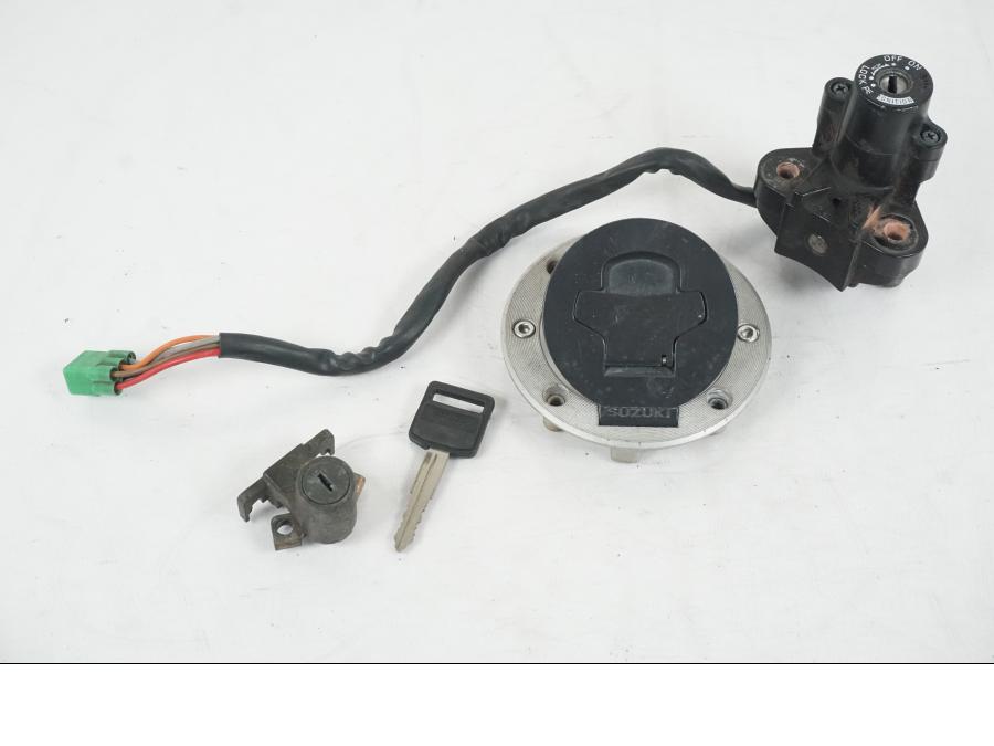 Framsidan på <p>Låssats från Suzuki TL 1000 S 1997.</p>

<p>Tändningslås, tanklock, sadellås och 1st nyckel.</p>

<p>Repor finns på tanklocket, slitage av lack på tändningslåset även att gummi skyddet för kabel har ett hål se bild.</p> motorcykel.