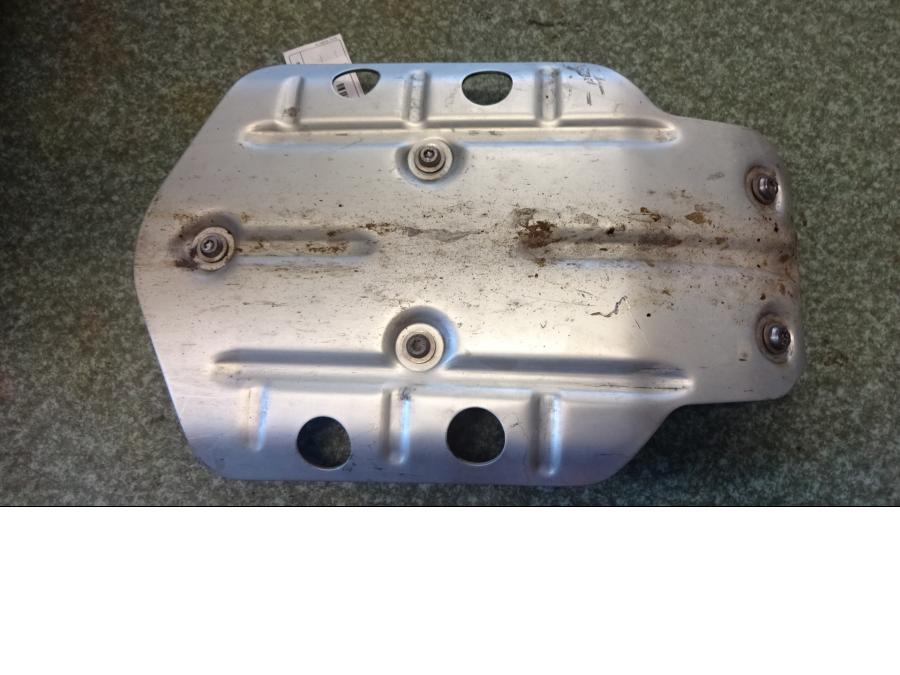 Baksidan på <p>Hasplåt från BMW R 1200 GS 2013.</p>

<p>Med fästen och bult, några repor på undersidan.</p> motorcykel.