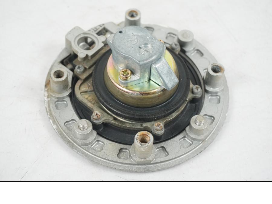 Snett nerifrån på <p>Låssats från Suzuki TL 1000 S 1997.</p>

<p>Tändningslås, tanklock, sadellås och 1st nyckel.</p>

<p>Repor finns på tanklocket, slitage av lack på tändningslåset även att gummi skyddet för kabel har ett hål se bild.</p> motorcykel.