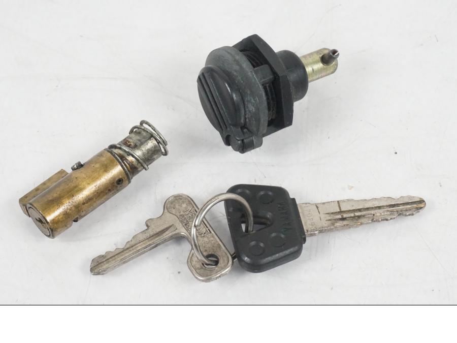 Baksidan på <p>Låssats från Yamaha XV 750 1993.</p>

<p>1st 1st nyckel, tändningslås, tanklock, tändningslås och</p>

<p>förvaringsfacklås Repor finns på tändningslåset se bild.</p> motorcykel.