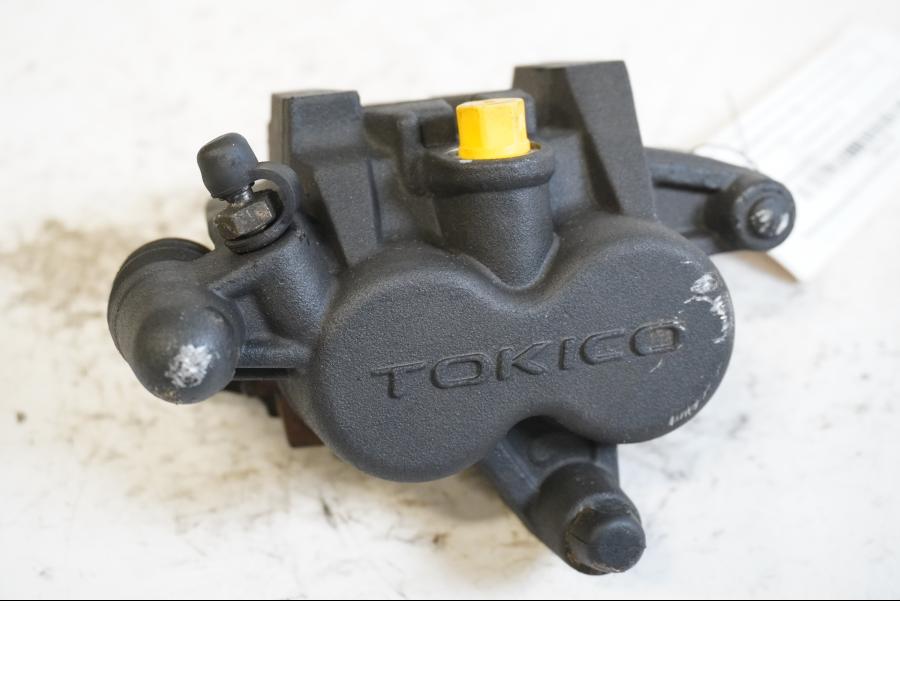 Framsidan på <p>Bromsok vänster fram Kawasaki ER-6N ABS 2014.</p>

<p>Tokico. Två kolvs ok. Lättare skrapmärken på oket.</p>

<p>Okej skick.</p> motorcykel.