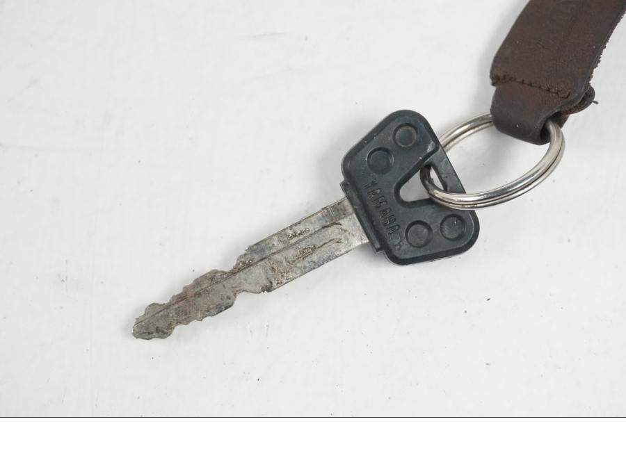 Baksidan på <p>Tanklock från Yamaha FZ-S 600 1998.</p>

<p>Med 1st nyckel och sadellås.</p> motorcykel.